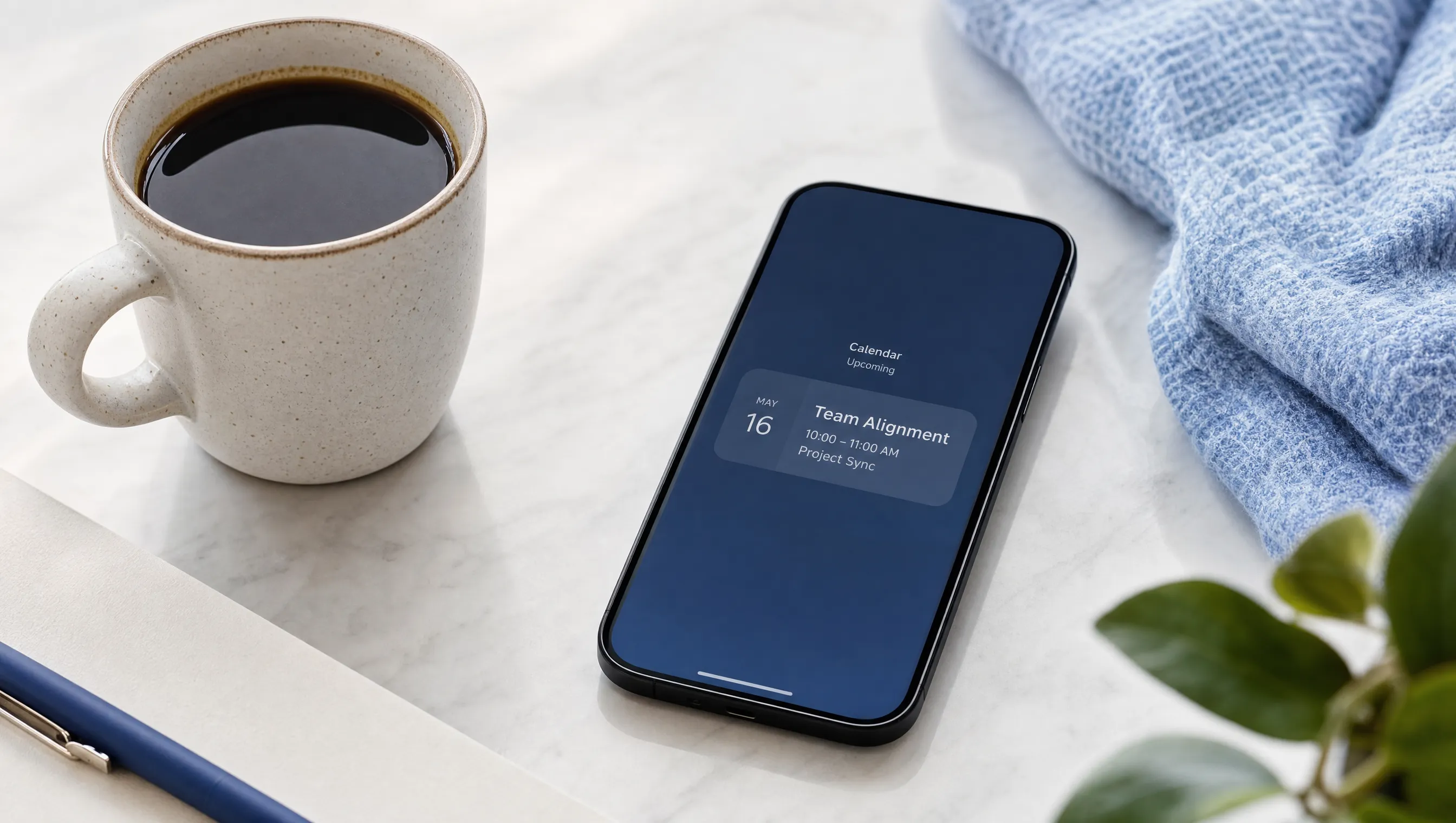 A coffee cup beside a phone showing a calendar event